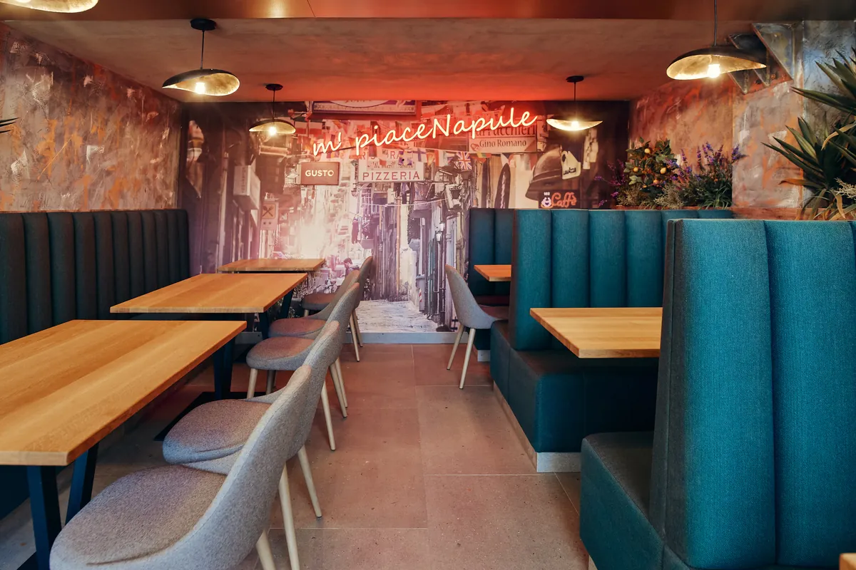 Jedilnica z neonskim napisom „m' piace Napule”, ulično muro in banjeti.